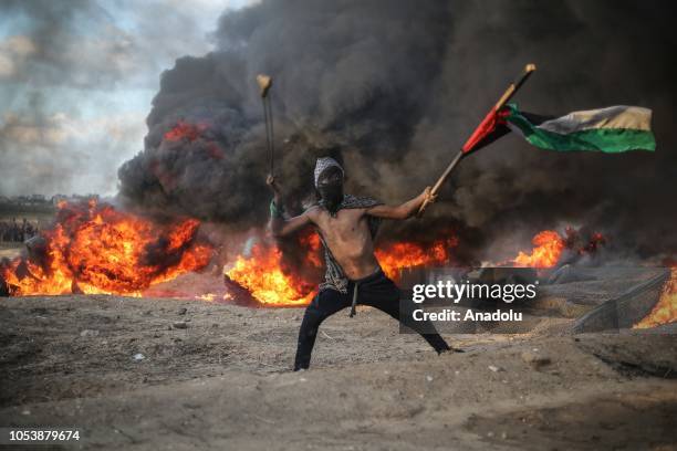 Palestinian demonstrators burn tyres and throw rocks using slingshots after the intervention of Israeli forces during the "Great March of Return"...