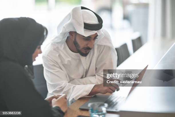empresarios unidos discutiendo sobre laptop - cultura de los emiratos árabes unidos fotografías e imágenes de stock