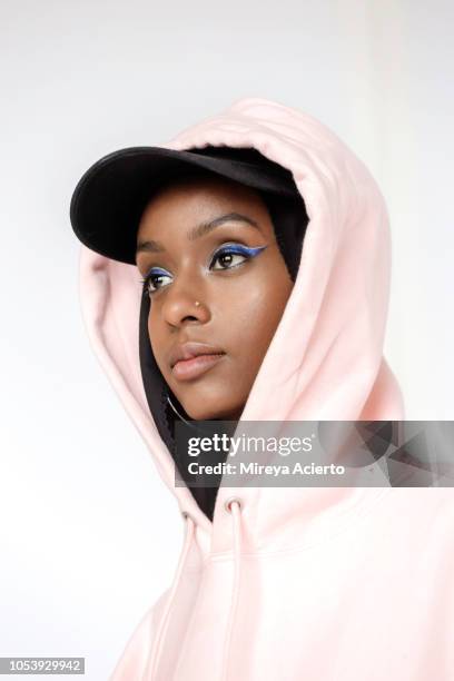 a portrait of a beautiful, young muslim woman wearing a black hijab, black baseball cap and a pink hoodie photographed in studio setting. - eye make up stock pictures, royalty-free photos & images