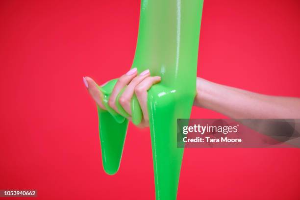 hand with slime on red background - goop stockfoto's en -beelden