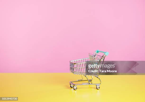 toy shopping trolley with pink  and yellow background - cart stock-fotos und bilder