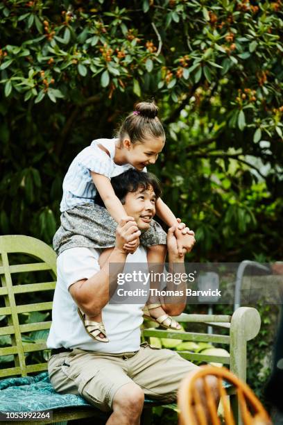 laughing young girl sitting on uncles shoulders in backyard garden - uncle fotografías e imágenes de stock