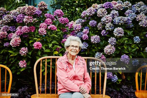 portrait of smiling senior woman sitting in backyard garden - mais de 90 anos - fotografias e filmes do acervo
