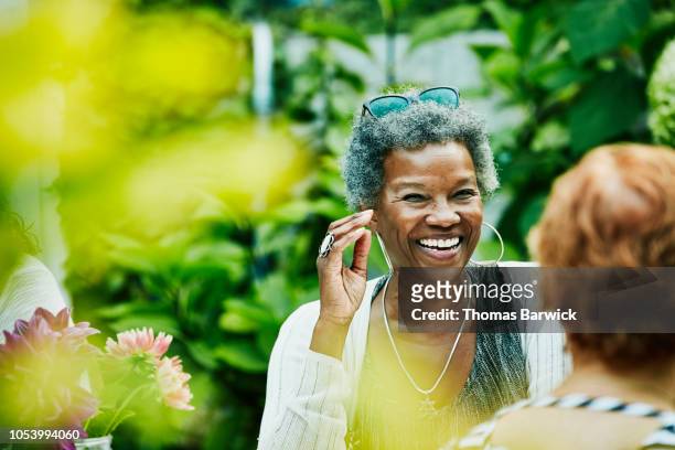 laughing woman hanging out with friends during backyard dinner party - wisdom stock pictures, royalty-free photos & images