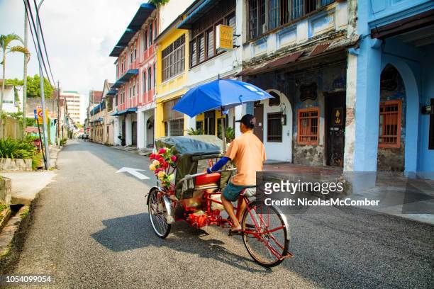 penang man drives a rickshaw in george town's historic district - georgetown imagens e fotografias de stock