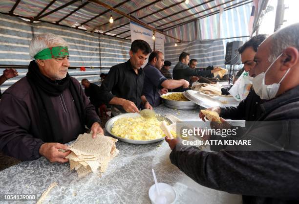 Men offer food to Iranian Shiite Muslim pilgrims at the Iranian-Iraqi Mehran border as they head towards the central Iraqi shrine city of Karbala on...