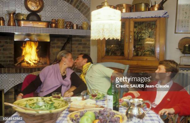 France - 9 décembre 1985 - L'acteur Claude BRASSEUR embrassant son épouse Michèle, en présence de leur fils Alexandre , autour d'un dîner en famille.