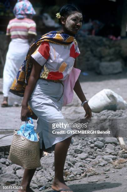 La vie sur l'île de MAYOTTE en avril 1986. Ici, une jeune femme mahoraise marchant. Elle porte des vêtements colorés, un panier à la main, et un...