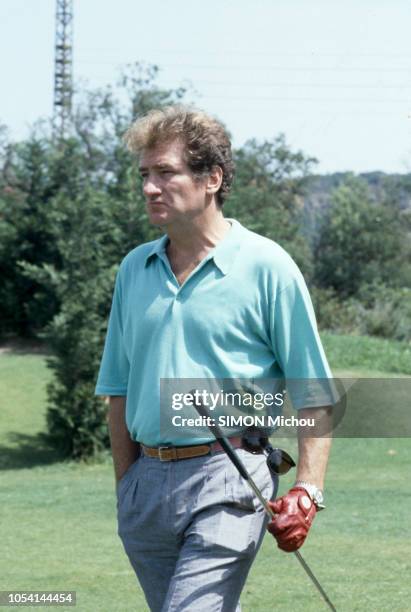 Saint-Tropez, France - Août 1985 - Le chanteur Eddy MITCHELL en vacances avec son épouse Muriel et leur fille Pamela. Ici, marchant en polo bleu...