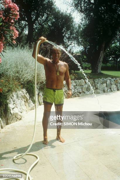 Août 1988 --- Jean-Paul BELMONDO en vacances en famille dans une villa de location, isolée dans les terres de Mougins : attitude de l'acteur en short...