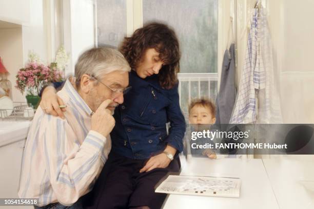 Paris, France - 28 février 1992 - Le réalisateur Maurice PIALAT, faisant des mots croisés avec son épouse Sylvie sur ses genoux, en présence de leur...