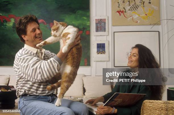 Paris, France - 24 mars 1994 - Le chanteur Gérard LENORMAN prenant dans ses bras son chat blanc et roux "lord Pounett", en présence de sa compagne...