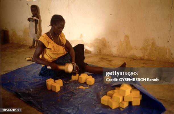 Différents aspects du Burkina Faso en avril 1994. Femme assise par terre fabriquant du savon.