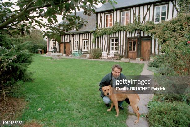 Normandie, France - Novembre 1995 - Le journaliste Franz-Olivier GIESBERT à Routot. Ici, accroupi auprès d'un chien, dans le jardin, devant la maison...