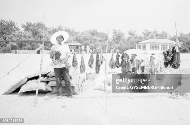 Chine, juillet 1985 --- Les Chinois à la plage à Beidaihe, station balnéaire de la province de Hebei. Ici, une femme coiffée d'un chapeau vendant des...