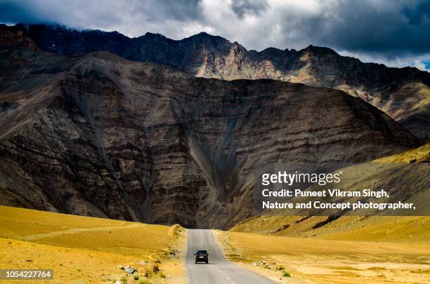 a car speeding on a mountain road surrounded by himalayan mountain range - indian road stock-fotos und bilder