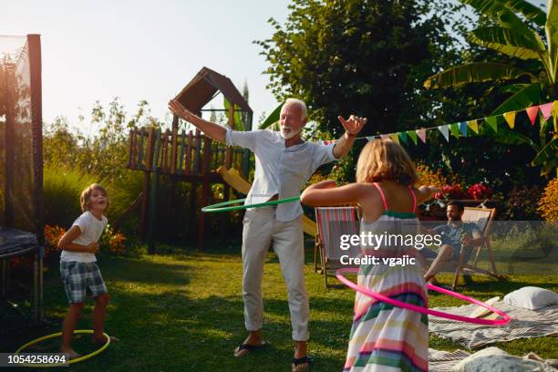 multi-generation familie hula hooping in hinterhof - gymnastikreifen stock-fotos und bilder