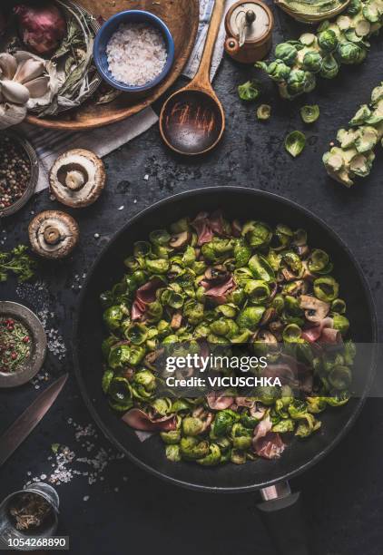 roasted brussels sprouts leaves with mushrooms and ham in black pan , top view - brussels sprout stock-fotos und bilder