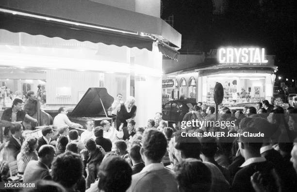 Alpes-Maritimes, France, juillet 1961 --- 2ème Festival international de jazz d'Antibes - Juan-les-Pins. Scène de rue en soirée, à la terrasse d'un...