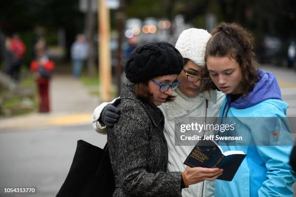 Tammy Hepps, Kate Rothstein and her daughter, Simone Rothstein pray from a prayerbook a block away from the site of a mass shooting at the Tree of...