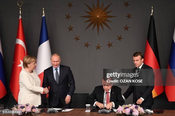 Russian President Vladimir Putin and German Chancellor Angela Merkel shake hands after a conference with Turkish President Recep Tayyip Erdogan and...