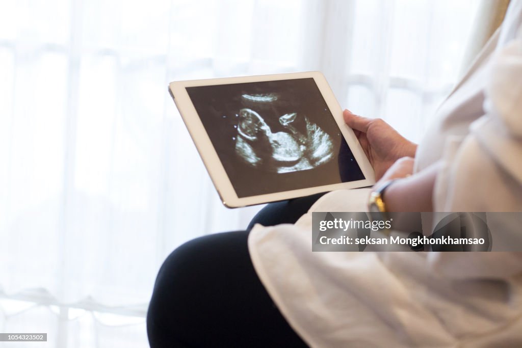 Pregnant Woman Showing Ultrasound Image On Digital Tablet