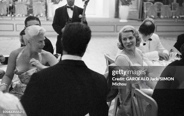 Le 9ème Festival de CANNES 1956 s'est déroulé du 23 avril au 10 mai : Ingrid BERGMAN assise à une table, se retournant pour discuter avec Jacques...