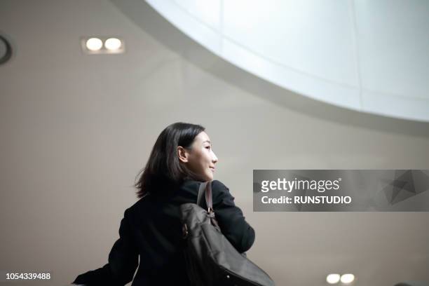 businesswoman standing on escalator - business stairs 個照片及圖片檔