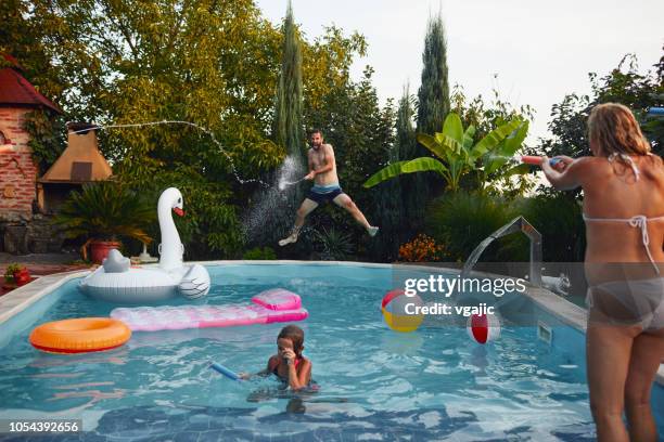 family water fight - young girl jumping into swimming pool stock pictures, royalty-free photos & images