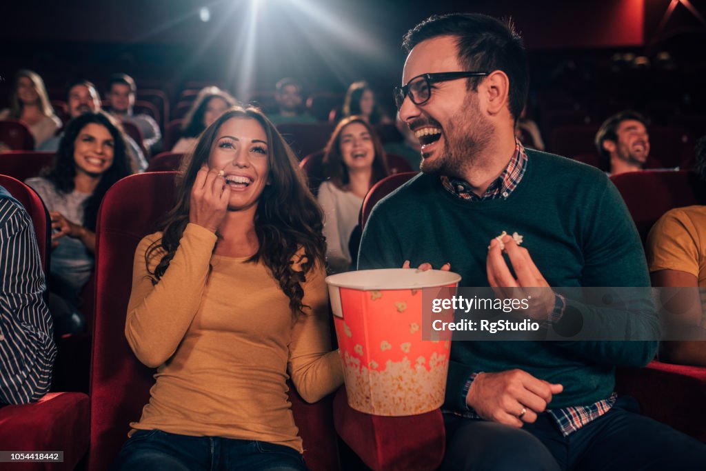 Amigos felices comiendo palomitas en el cine