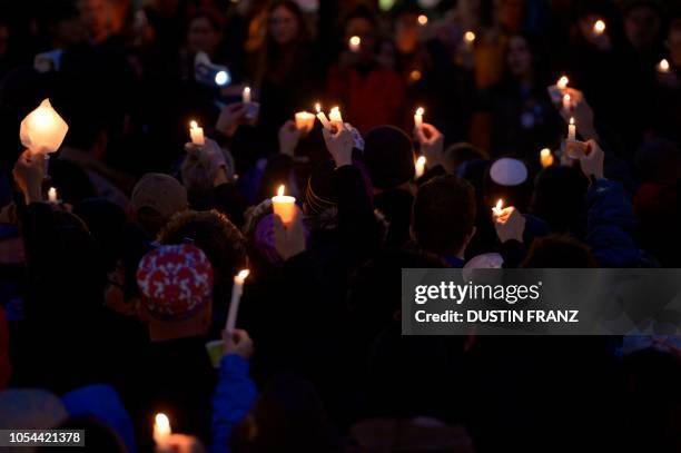 Members of the Squirrel Hill community hold up lit candles as they come together for a student-organized candle vigil in rememberance of those who...