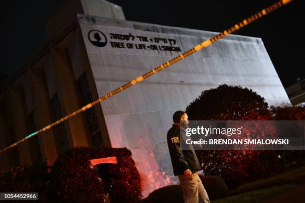 An FBI agent stands behind a police cordon outside the Tree of Life Synagogue after a shooting there left 11 people dead in the Squirrel Hill...