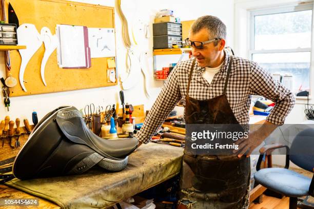 a saddle maker with one of his handmade saddles. - saddler stock pictures, royalty-free photos & images