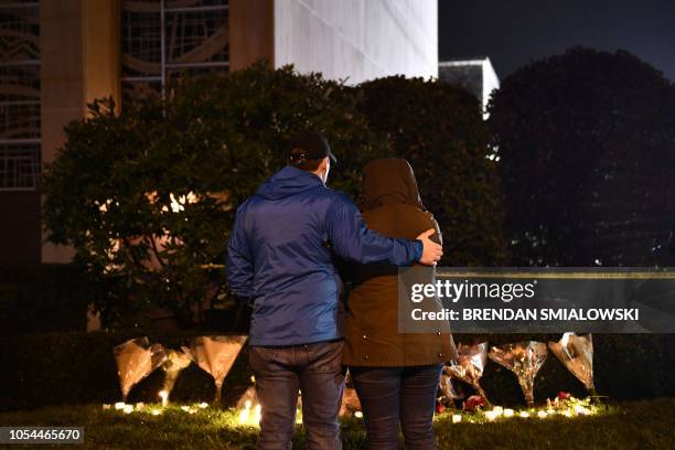 Lorea Stallard and her husband Kyle Parker stand in front of flowers and candles placed below a police cordon outside the Tree of Life Synagogue...