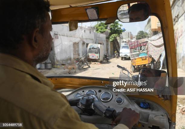 In this picture taken on October 16 Pakistani auto-rickshaw driver Mohammad Rasheed drives his rickshaw in Korangi, a slum area in the eastern...