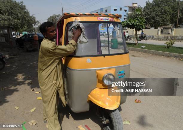 In this picture taken on October 16 Pakistani auto-rickshaw driver Mohammad Rasheed cleans his rickshaw in Korangi, a slum area in the eastern...