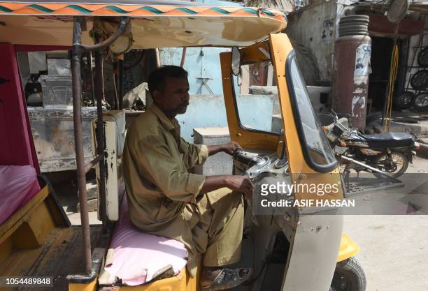 In this picture taken on October 16 Pakistani auto-rickshaw driver Mohammad Rasheed drives his rickshaw in Korangi, a slum area in the eastern...