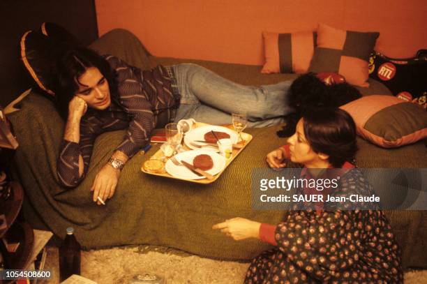 Paris, France, 1er février 1976 --- Le chanteur Nicolas PEYRAC chez lui à Paris avec son épouse Valentine. Tous deux installés sur un lit, lui fumant...