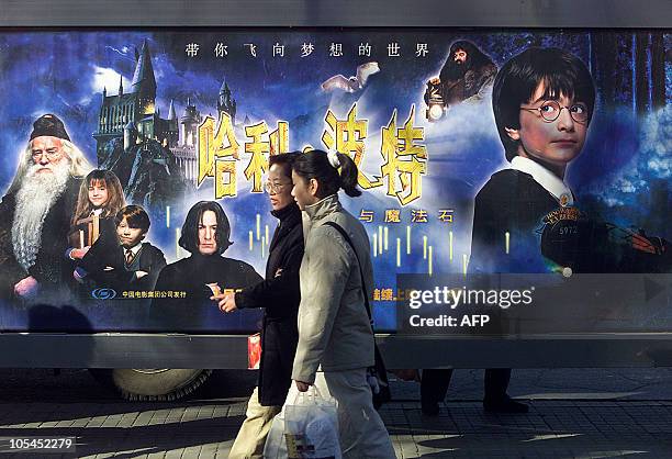 Women walk past a billboard at a Beijing bus stop advertising the release of the film "Harry Potter and the Sorcerer's Stone", 29 January 2002. The...