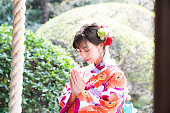 Attractive asian woman wearing japanese kimono praying at a Shinto shrine.