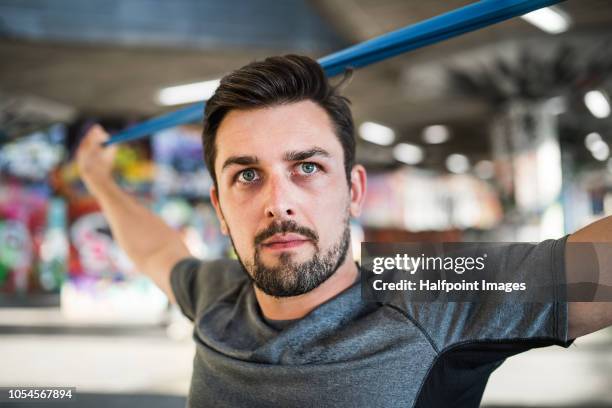 young sporty man doing stretching with resistance bands under the bridge outside in a city. - england slovakia stock pictures, royalty-free photos & images