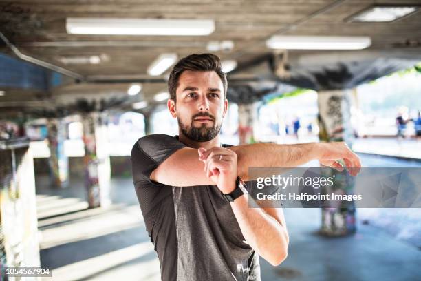 young sporty man doing stretching under the bridge outside in a city. - england slovakia stock pictures, royalty-free photos & images