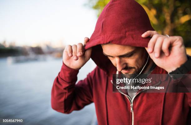 young sporty man with earphones standing on river promenade outside in a london city, listening to music. - england slovakia stock pictures, royalty-free photos & images