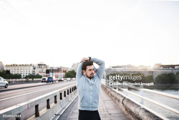 young sporty man stretching arms on the bridge outside in a city. - england slovakia stock pictures, royalty-free photos & images