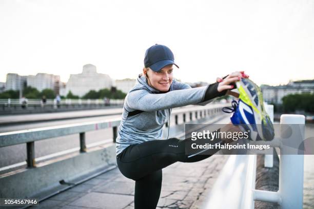 young sporty woman stretching legs on the bridge outside in a city. - england slovakia stock pictures, royalty-free photos & images