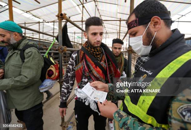 An Iranian policeman checks the travel document of a pilgrim at the Mehran border point between Iran and Iraq, as thousands of Shiite Muslim Iranian...