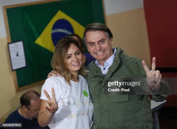 Jair Bolsonaro, far-right lawmaker and presidential candidate of the Social Liberal Party , poses with his wife Michelle as they arrive to cast their...