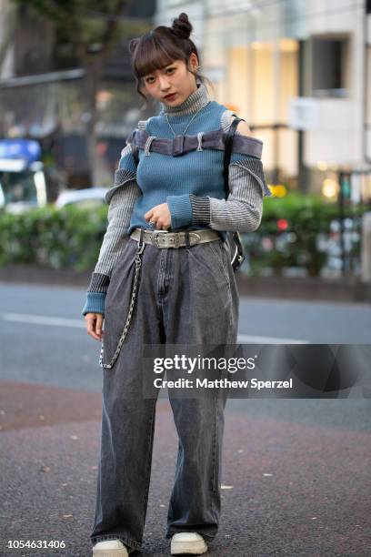 Local is seen on the street in Harajuku wearing black Unif backpack, blue/grey sweater with straps, grey pants, white shoes and pocket chain on...