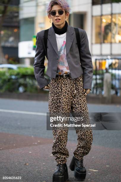Local is seen on the street in Harajuku wearing grey blazer, leopard print gloves and pants, black platform shoes, black sweater, white graphic shirt...