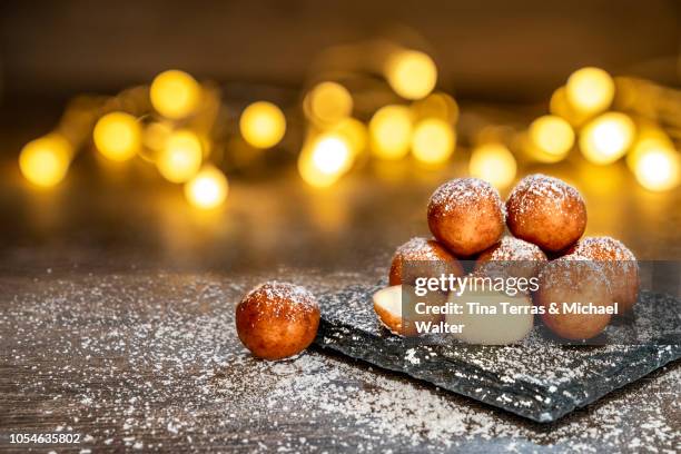 marzipan balls with powdered sugar on wooden board with slate plate and candlelight. - marzipan stock pictures, royalty-free photos & images